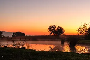 The sun rises over a small dam in the high veld winter landscape near Hartebeespoort The sun rises over a small dam in the high veld winter landscape near Hartebeespoort