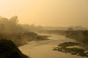 The sun rising over a small foggy river early in the morning, Chitwan National Park The sun rising over a small foggy river early in the morning, Chitwan National Park