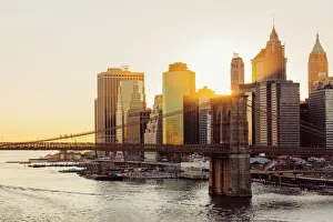 Sunset over Brooklyn Bridge and skyline of Manhattan Financial District in Downtown Sunset over Brooklyn Bridge and skyline of Manhattan Financial District in Downtown