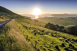 Sunset over grassland and a country road, Dunedin Beach at the back, Otago Peninsula Sunset over grassland and a country road, Dunedin Beach at the back, Otago Peninsula