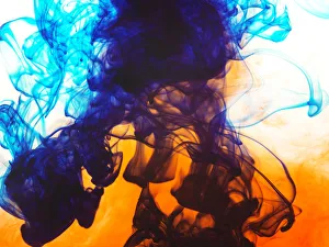 Swirls of spreading orange and blue ink in liquid