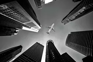 Cities Gallery: Tall city buildings and a plane flying overhead