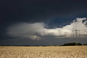 Thick storm clouds gathering over a field of rye with power poles, Bavaria, Germany Thick storm clouds gathering over a field of rye with power poles, Bavaria, Germany