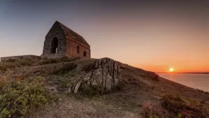 Prints of Low angle view of Rame Head against a clear sky. On the horizon you can see the sun disappearing into the sea Cornwall Prints: Rame Head Low Angle View Print