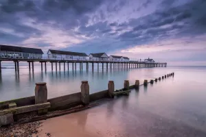 Prints of Southwold pier, Suffolk, UK. August 04, 2018. Image shows Southwold pier at dawn with the tide in motion. Dramatic clouds scatter the sky Suffolk Prints: Southwold Pier Print at Dawn, Suffolk Coast
