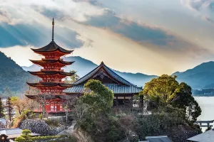 Prints of Miyajima, Hirosihima, Honshu, Japan - February 8th 2018: a red shinto Pagoda captured in afternoon light with dramatic clouds Travel Imagery Prints: Miyajima Pagoda Print