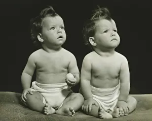 Twin brothers (9-12 months) sitting on blanket, (B&W), portrait Twin brothers (9-12 months) sitting on blanket, (B&W), portrait