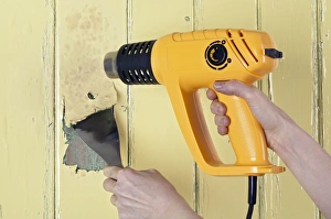 Using a heat gun and scraper to strip paint from a wooden surface Using a heat gun and scraper to strip paint from a wooden surface