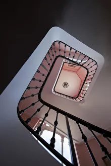 <b class=qtipBold><figcaption>View of stairwell looking up</figcaption></b><br>Upward view of a spiral rod iron stairwell with pink walls and white ceilings.<br><em>© Marie Hickman</em> View of stairwell looking up