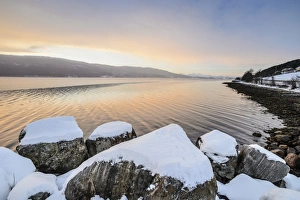 Winter atmosphere at sunrise on the fjord, snow-covered rocks, coastal road, near Alesund, Norway Winter atmosphere at sunrise on the fjord, snow-covered rocks, coastal road, near Alesund, Norway