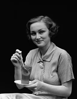 Woman in checked dress, stirring a glass of iced tea, portrait Woman in checked dress, stirring a glass of iced tea, portrait
