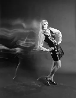Woman with long blond hair wearing vinyl dress and scarf around neck with hands on hips Woman with long blond hair wearing vinyl dress and scarf around neck with hands on hips