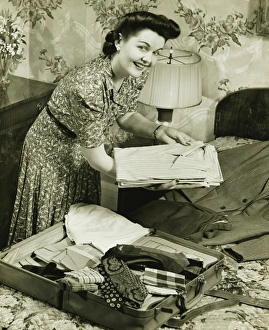 Woman putting clothes into suitcase, (B&W) Woman putting clothes into suitcase, (B&W)