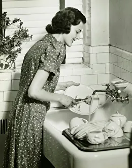 Woman washing dishes at kitchen sink, (B&W) Woman washing dishes at kitchen sink, (B&W)