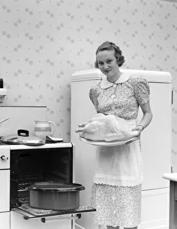 Domestic Life Gallery: Woman Wearing An Apron Over A White Collar Cotton Print Dress Is Standing In Front Of An