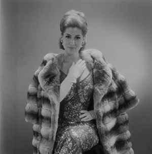Woman wearing fur coat sitting against grey background Woman wearing fur coat sitting against grey background