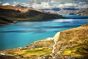 <b class=qtipBold><figcaption>Yamdrok Tso Lake</figcaption></b><br>Small village on rolling green hills next to Yamdrok-tso lake as it glows bright turquoise blue in Tibetan sun.<br><em>© 2011 Nicole Kucera</em> Yamdrok Tso Lake