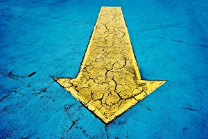 Yellow arrow on blue concrete with cracks Yellow arrow on blue concrete with cracks