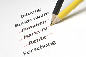 A yellow and a black pencil crossing out the letterings Familien, Hartz IV and Rente, German for families, Hartz IV A yellow and a black pencil crossing out the letterings Familien, Hartz IV and Rente, German for families, Hartz IV