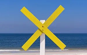 A yellow wooden cross marks a shoal near the shore at the beach, near Kampen, Sylt A yellow wooden cross marks a shoal near the shore at the beach, near Kampen, Sylt