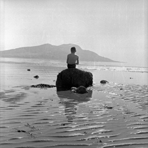 A young boy sitting on a rock in the sea just off the Isle of Arran A young boy sitting on a rock in the sea just off the Isle of Arran