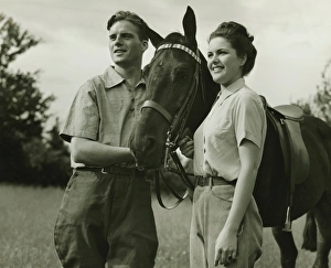 Young couple standing with horse in field, (B&W) Young couple standing with horse in field, (B&W)