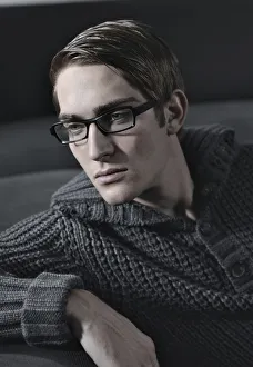 Young man wearing glasses sitting on a sofa Young man wearing glasses sitting on a sofa