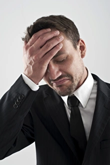 Young man wearing a suit holding his hand on his forehead, worried Young man wearing a suit holding his hand on his forehead, worried