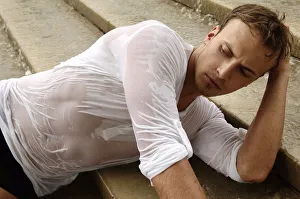 Young man wearing a wet shirt, lying on stairs Young man wearing a wet shirt, lying on stairs