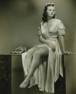 Young woman in elegant dressing gown sitting in studio, (B&W) Young woman in elegant dressing gown sitting in studio, (B&W)