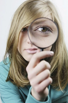 Young woman with magnifying glass in front of her eye Young woman with magnifying glass in front of her eye