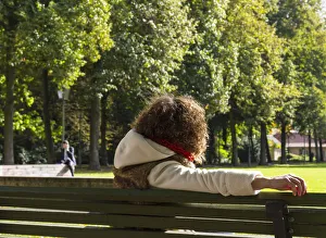 Young woman sitting on a bench watching a man speaking on the phone, Berlin, Germany, Europe Young woman sitting on a bench watching a man speaking on the phone, Berlin, Germany, Europe