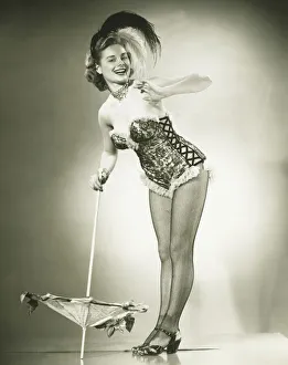 Young woman standing in studio, leaning against umbrella, (B&W) Young woman standing in studio, leaning against umbrella, (B&W)