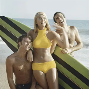 Young women and men with surfboard on beach, smiling Young women and men with surfboard on beach, smiling