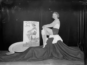 Railway Poster Prints: A photograph print of June Clyde posing with a Holiday Girl poster