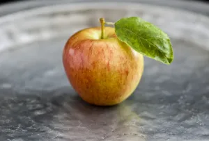 Apple with leaf on pewter charger credit: Marie-Louise Avery / thePictureKitchen