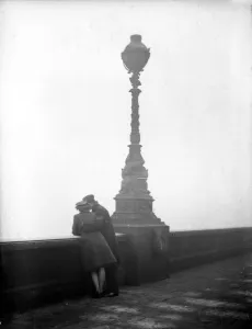 Couple arm in arm leaning over bridge in London in fog 1940s love couple romance Couple arm in arm leaning over bridge in London in fog 1940s love couple romance