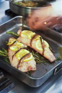 Fillets of monkfish in pan ready to be roasted on bed of rosemary with lemon Fillets of monkfish in pan ready to be roasted on bed of rosemary with lemon