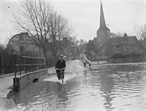 Flooding in Eynsford, Kent. Cyclist rides through the water. 1937