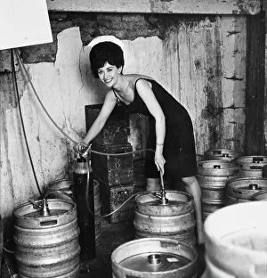 Stock Agency Gallery: Glamour in the cellar as barmaid Lois taps another barrel of beer. 19 October 1963