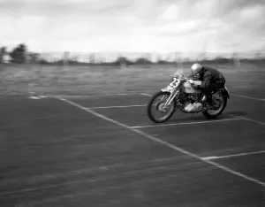 John Surtees speeds over the finishing line at the race track on his Vincent motorbike John Surtees speeds over the finishing line at the race track on his Vincent motorbike