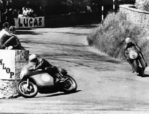 Prints of Mike Hailwood leads Rhodesias Gary Hocking as they go into the last lap in the Junior (350cc). International TT Race on the Isle of Man Isle Of Man Prints: A black and white print of two motorcyclists racing on the Isle of Man