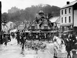 Prints of A Somerset Hunt - The West Somerset Foxhounds moving off in the High Street of Dunster - Near them is the Yarn Market which has recently been restored for preservation as an ancient monument Somerset Prints: A Print of a Somerset Hunt Scene