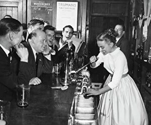 Stock Agency Gallery: A woman barmaid pulls a pint of beer for male customers in a London pub, England. 1950s