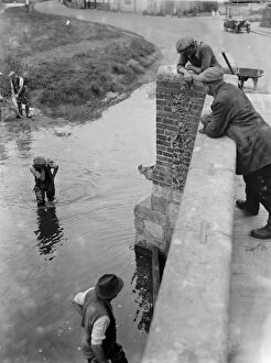 Workmen wade through the water crossing at the Eynsford bridge over the River Darent