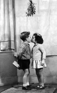 Young boy and girl kissing underneath the mistletoe at Christmas time 1956 love Young boy and girl kissing underneath the mistletoe at Christmas time 1956 love