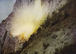 British Royal Marines in training, climbing a cliff while under fire from live ammunition and exploding ground charges