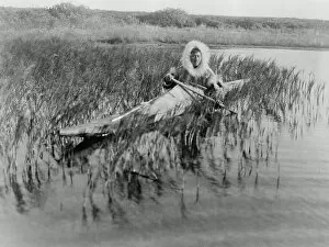 Hunters Gallery: An Eskimo muskrat hunter paddling through the marsh, Kotzebue, Alaska, c.1929 (b/w photo)