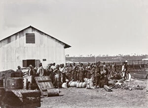 In Costume Gallery: Group of indigenous people in front of a warehouse in Uganda, Uganda, Africa, c.1901