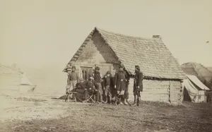 A group of soldiers, and two young men, one an African American, stand outside of A group of soldiers, and two young men, one an African American, stand outside of